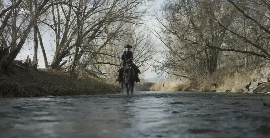 Man riding horse in shallow river water