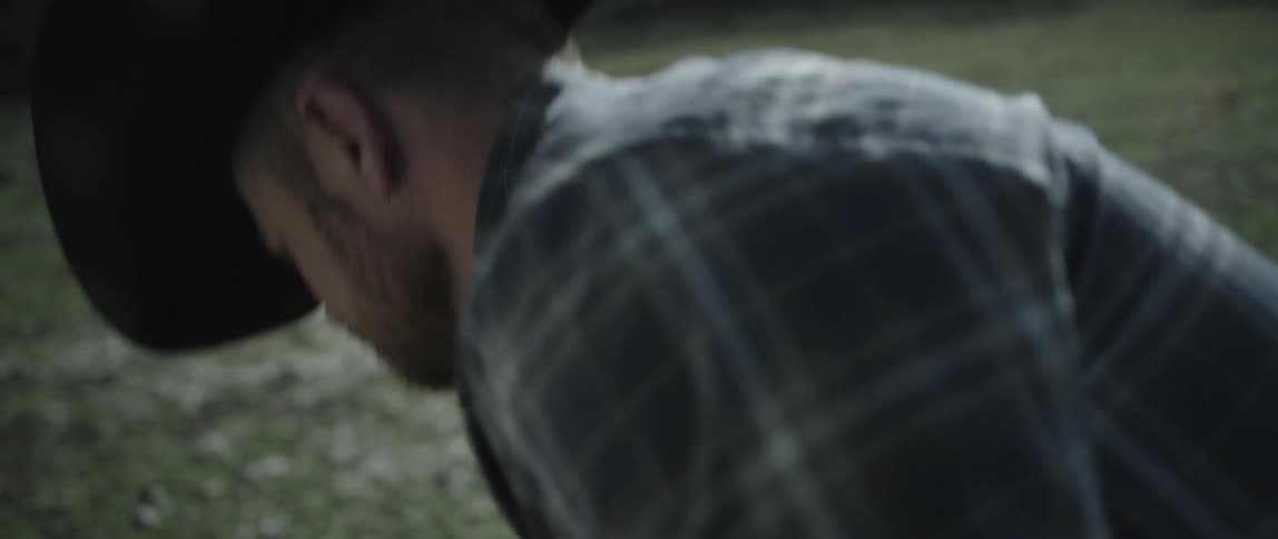 A man carrying a saddle puts it down on the grass
