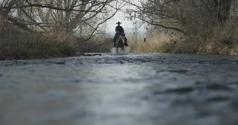 A man riding a horse is traveling through water