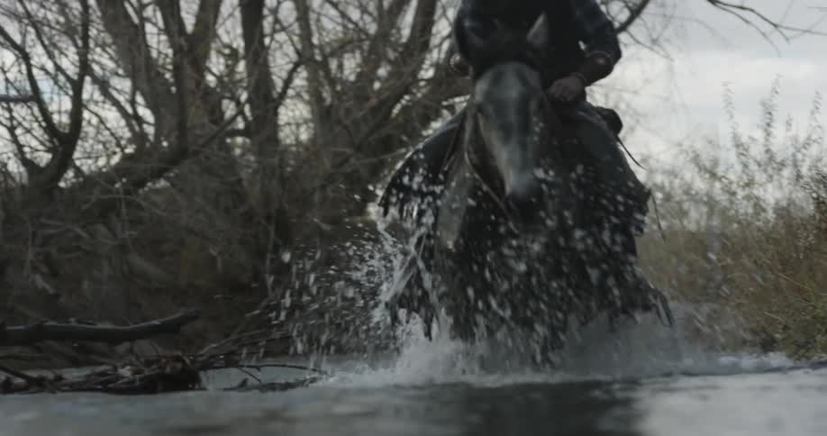 A man is riding his horse slowly through a stream