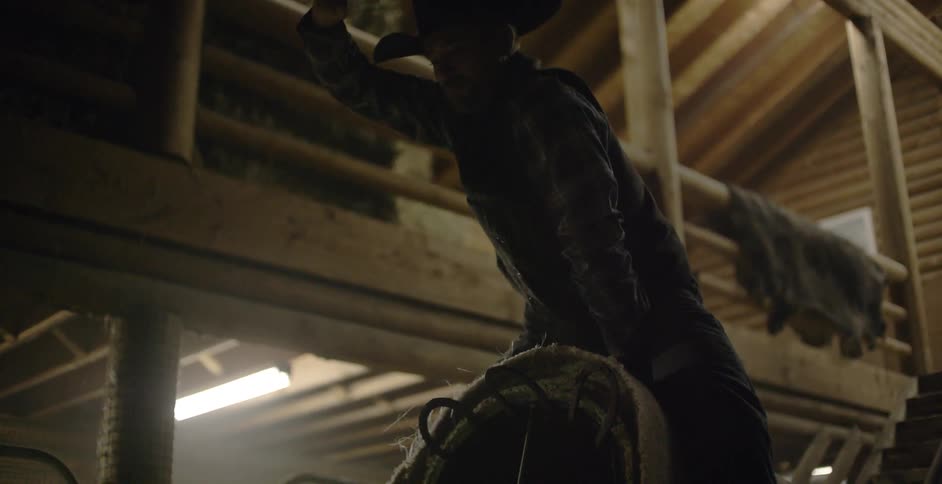 A man wearing a cowboy hat rides a mechanical bull