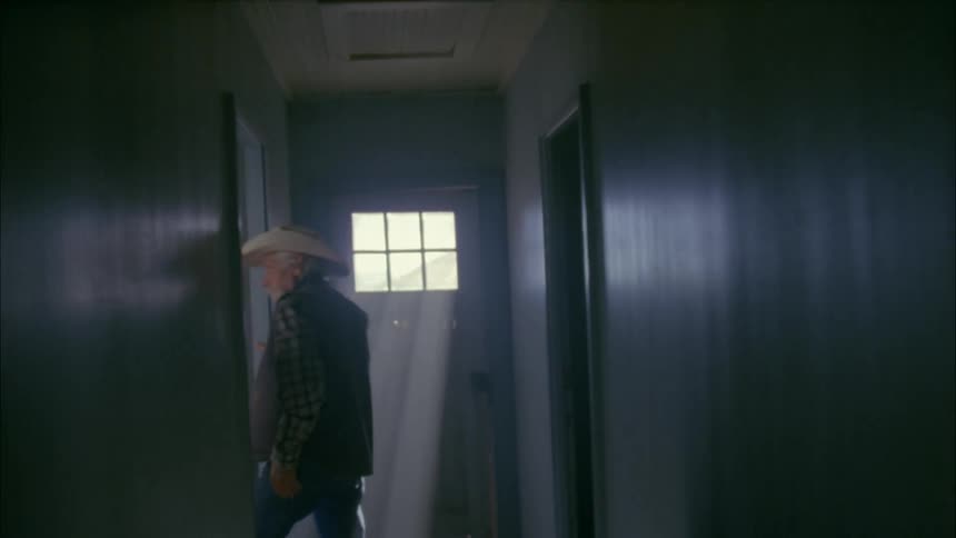 A man exits into a dark hall searching around