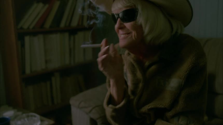 An old man lights a cigarette for an old blind woman