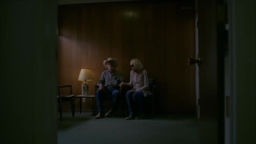A man and woman hold hands while sitting in a waiting room