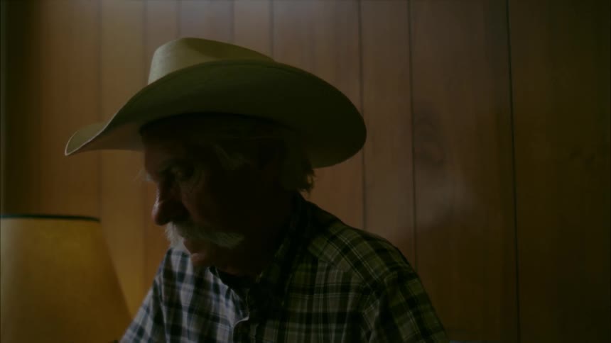 A man wearing a cowboy hat looks around