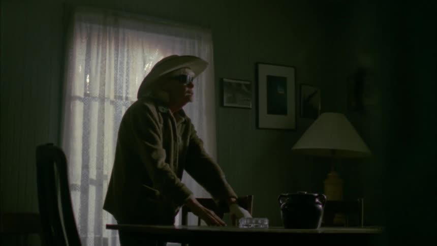 A woman feels around a table stumbling over a chair