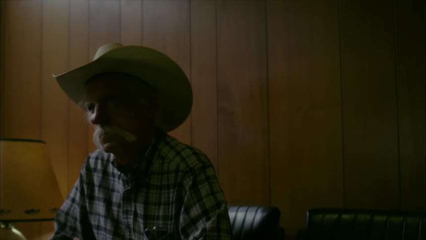 An old cowboy sits in a waiting room
