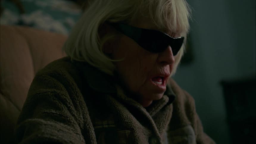 An elderly woman wraps her hand with tape and grimaces
