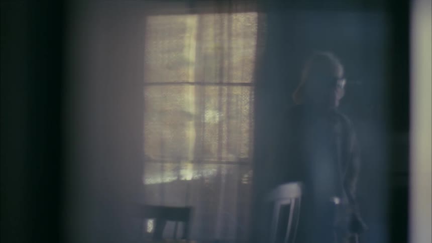 An old, blind woman is standing alone in a room