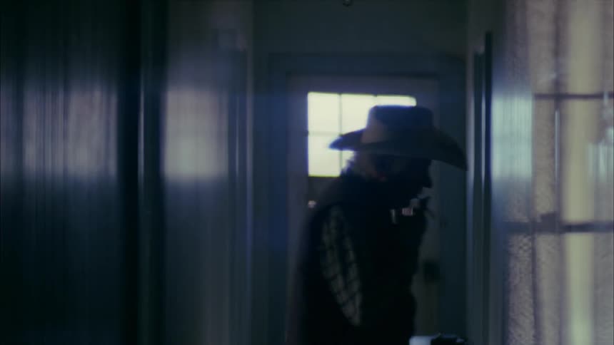 A man smoking a cigarette steps into a hallway