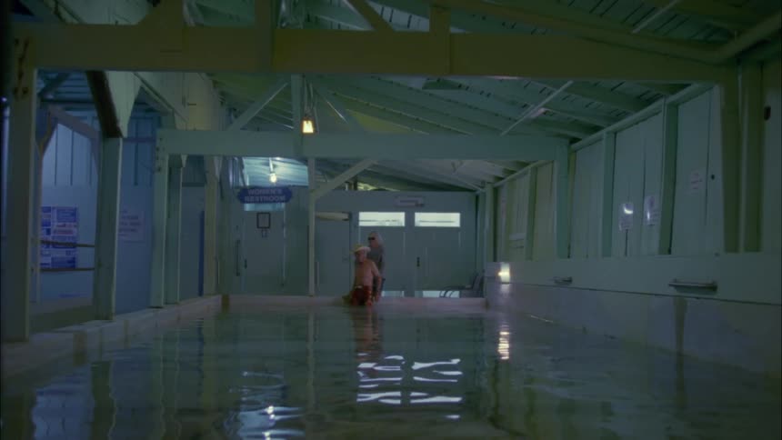 An elderly couple approach a spa bath and the man climbs in
