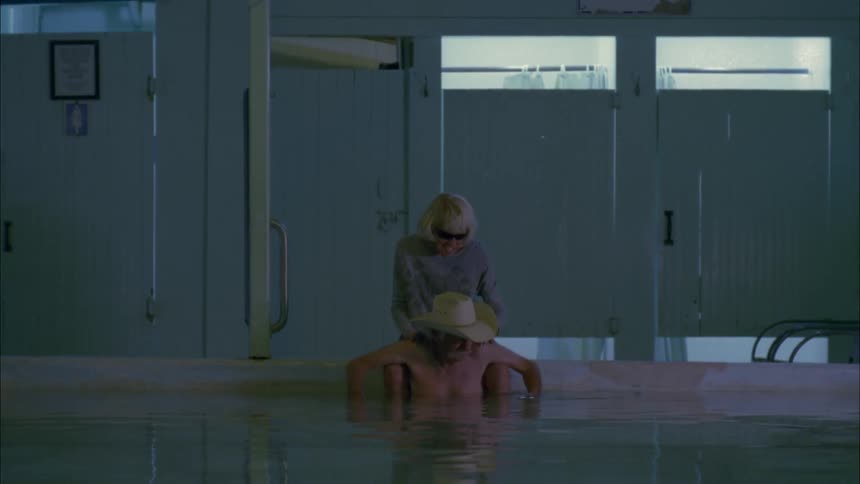 A woman massages a man's shoulders while he sits in a large pool of water