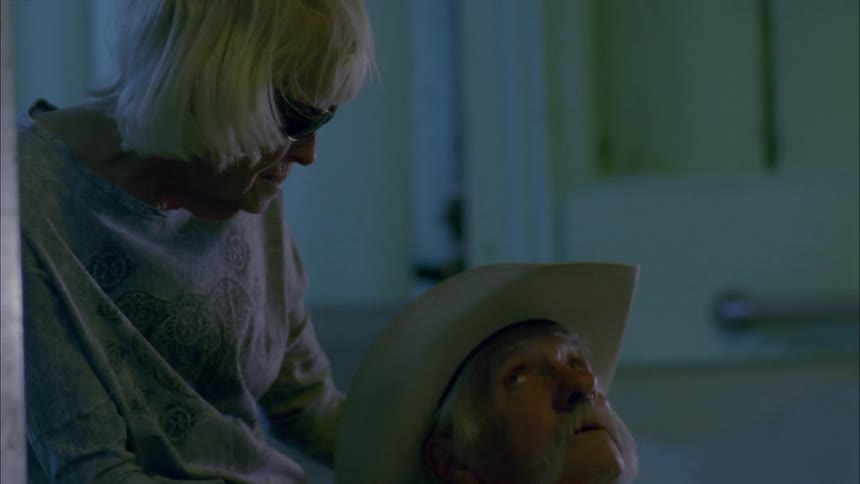 A woman massages the shoulders of a man in a cowboy hat