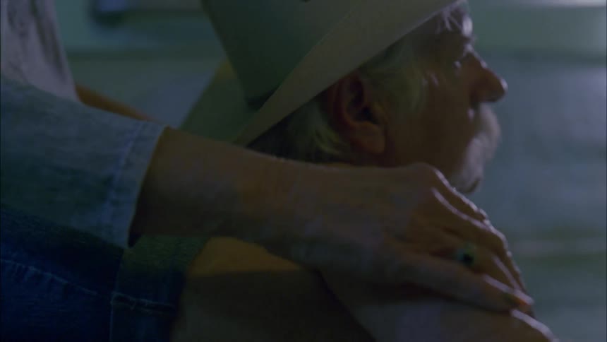 A woman rubs the shoulder of a man sitting in water