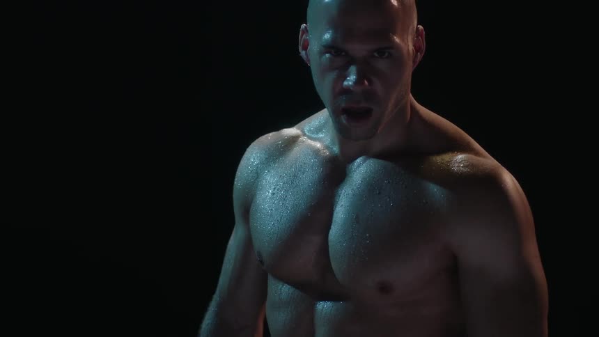 A bald man takes a deep breath in a dark area