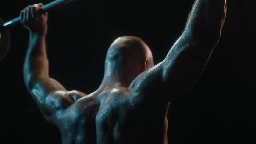 A man lifts weights in the dark
