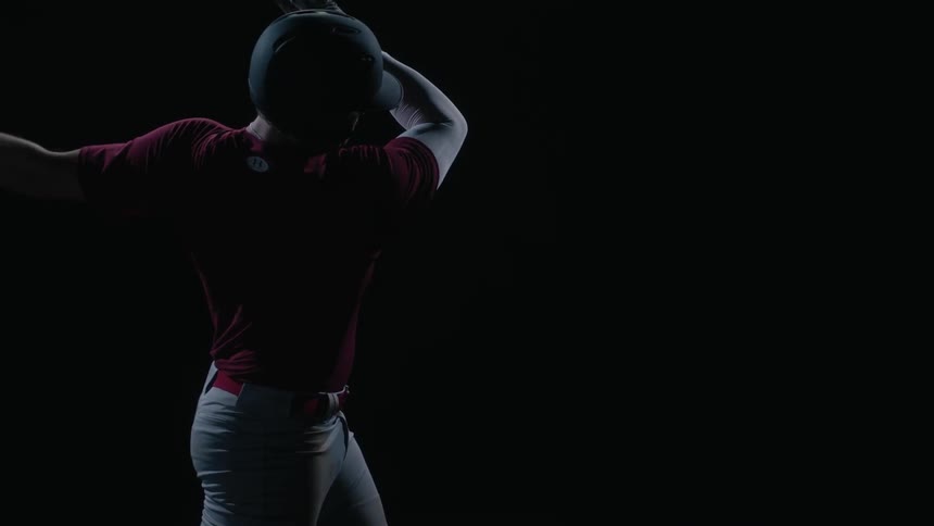 Man swings a baseball bat in a dark area