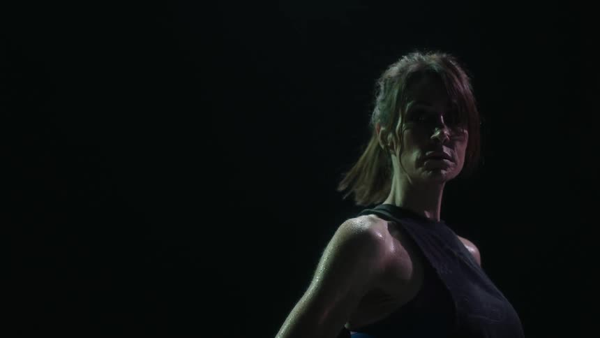 Woman standing still against a black background