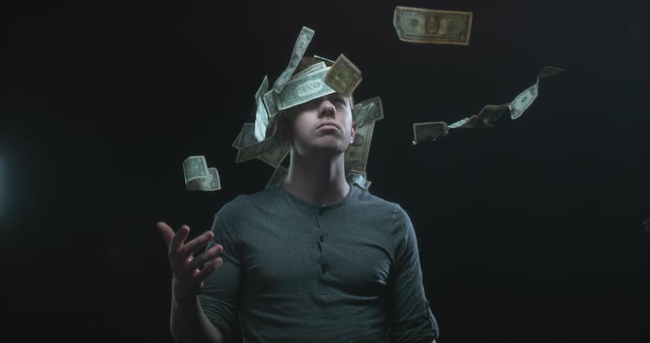 Dollar bills being thrown over a mans face