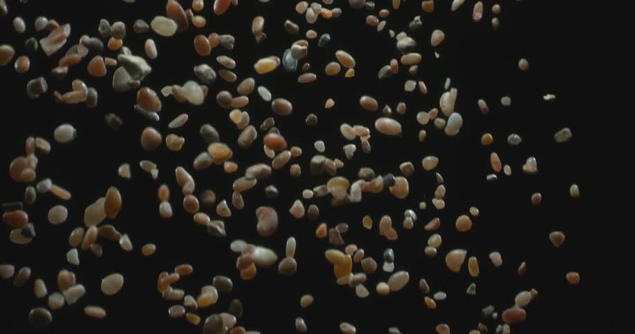Close up of various seeds falling against a black background