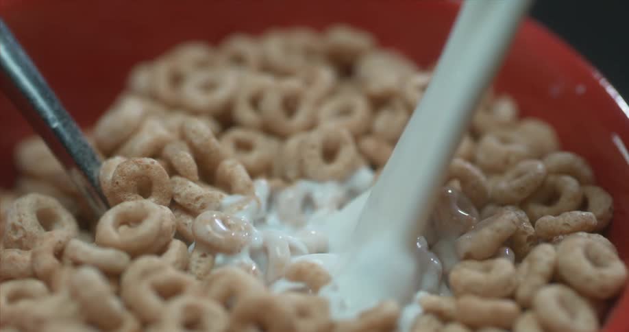 Slow motion shot of milk being poured over cereal