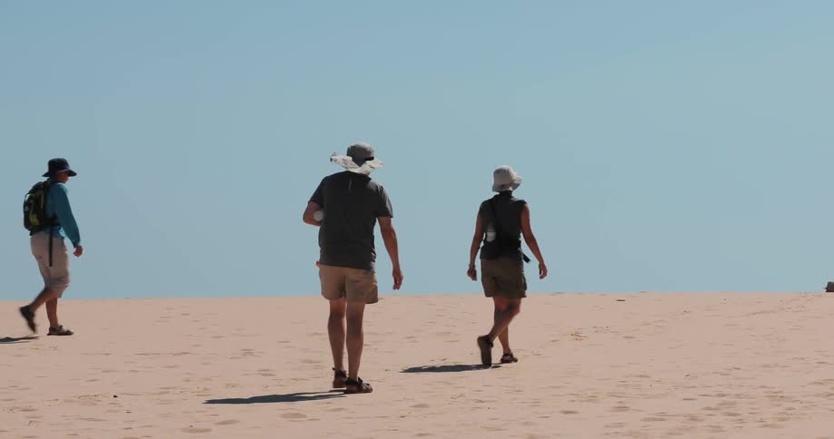 People walk up a sandy slope