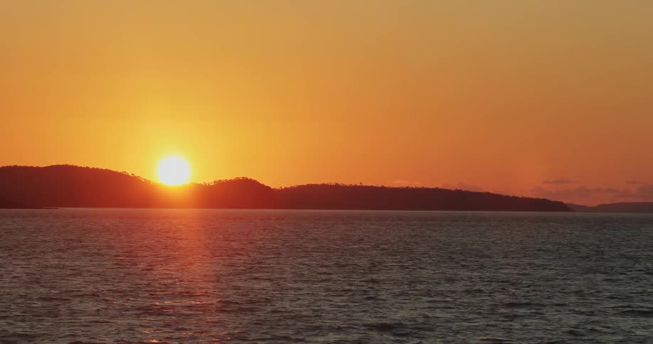 The sun rises over a body of water