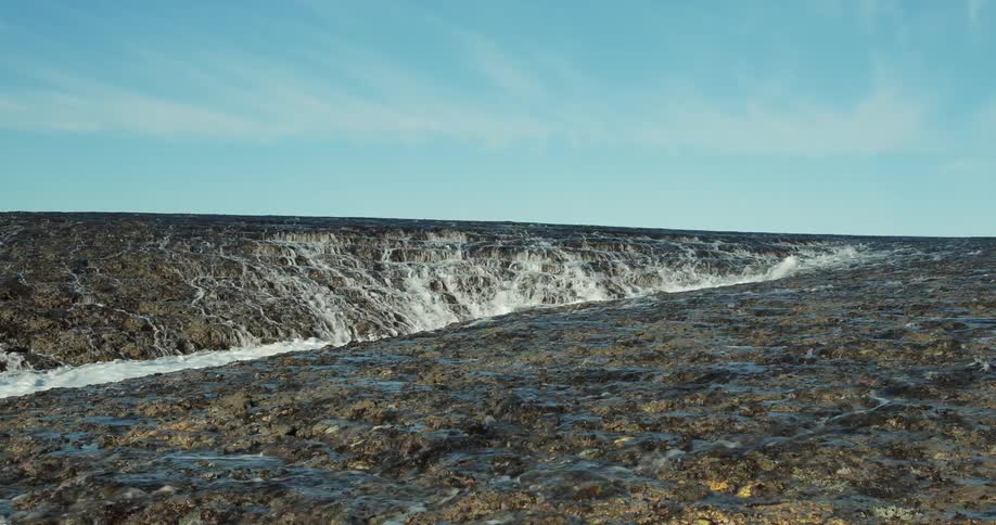 Water ripples and flows over a rock surface