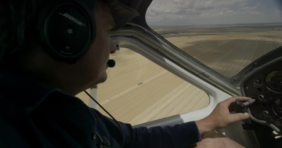 Man flying plane over farmland on cloudy day