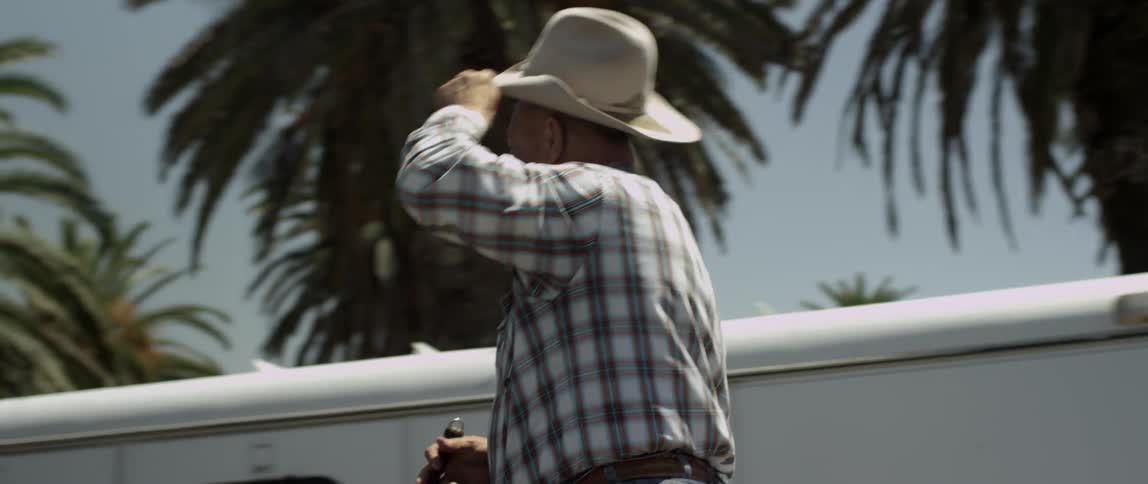 A man riding on a horse in the city near vehicles