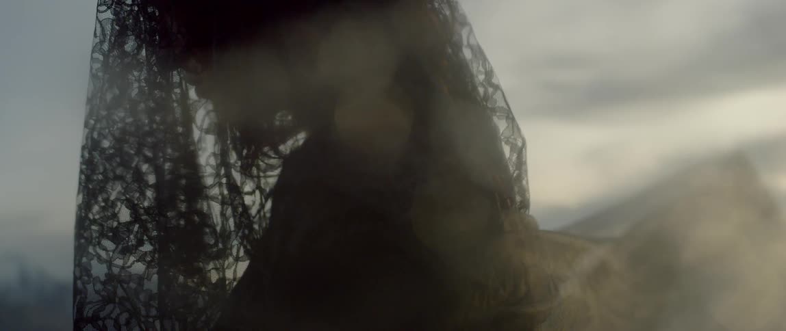 A woman wears a black veil over her face and the wind blows through it