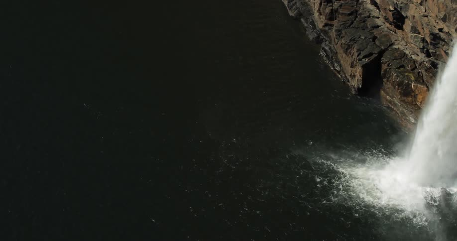 A waterfall rushes over the cliff and into the water below