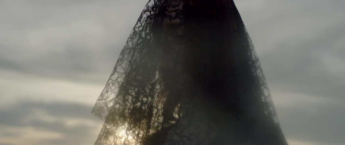 A woman wears a black lace veil over her face