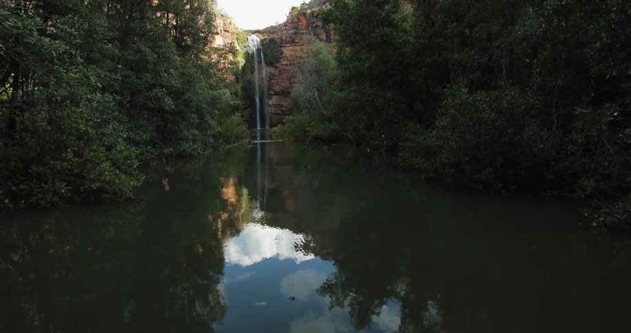 Water falls off a cliffside into a river