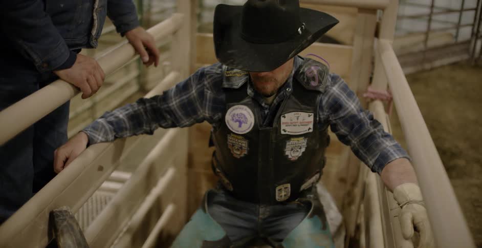 Man wearing cowboy hat sitting on bull at rodeo