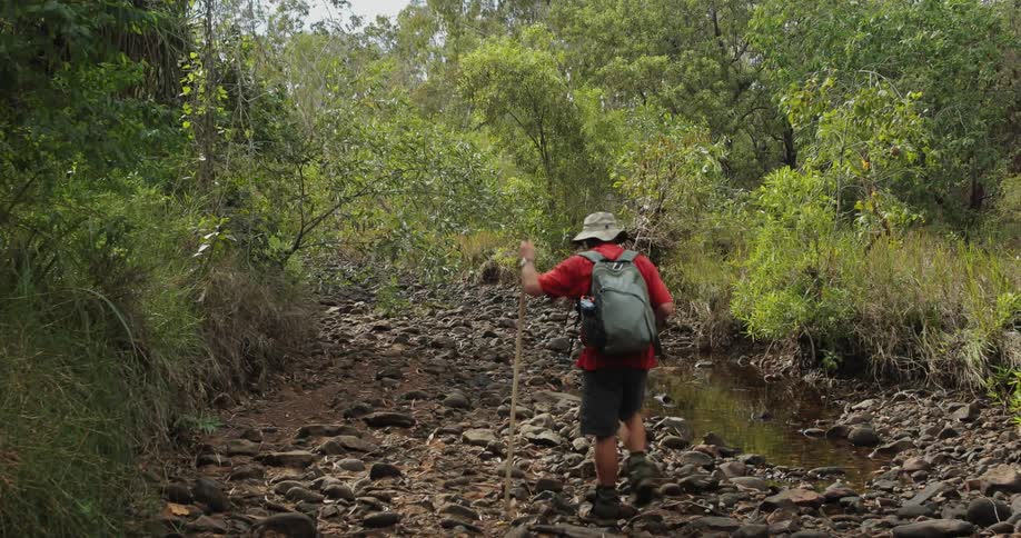 A man hikes through a stream