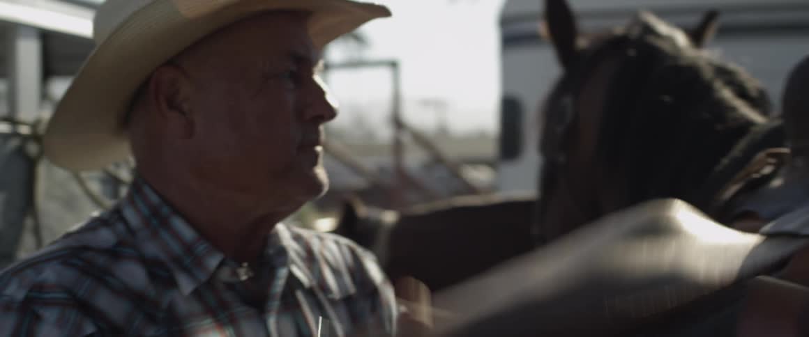 A man puts a saddle on a horse