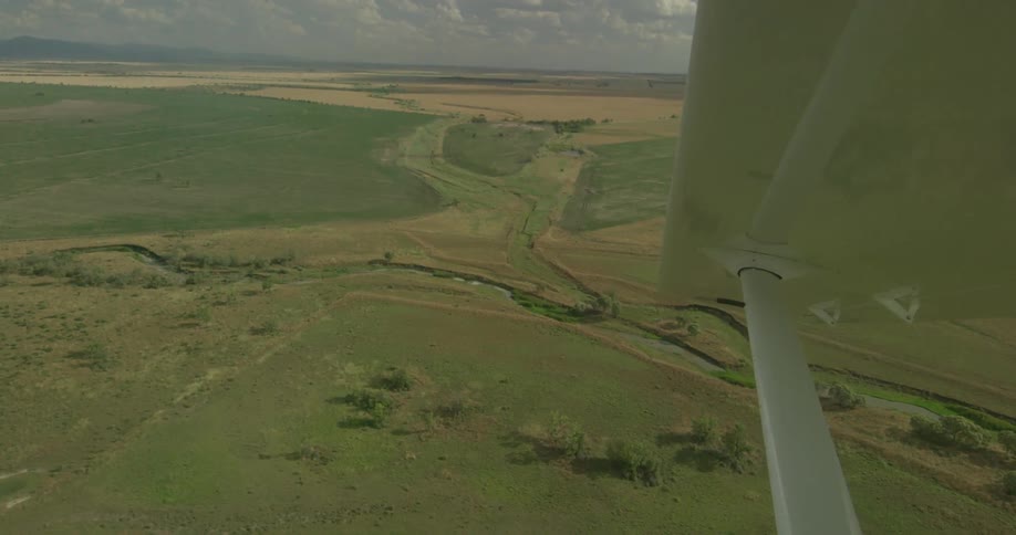 A plane is flying over a river flowing across a valley