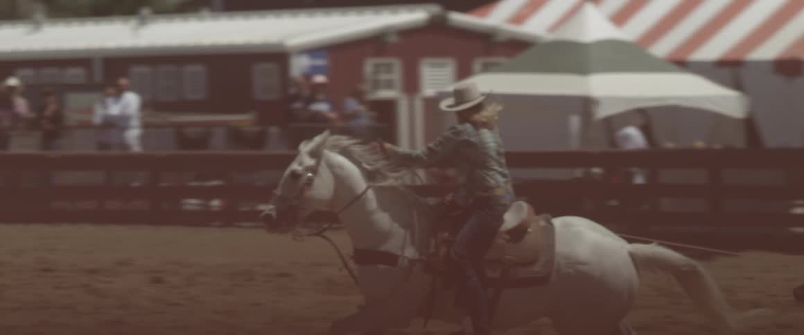 A cowgirl rides a horse at a rodeo