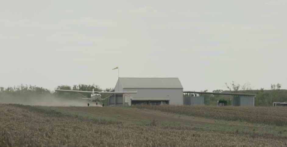 A small aircraft takes off from a rural field