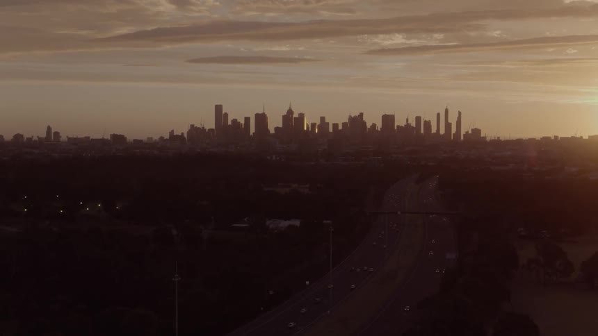 Cars traveling on freeway in large city at sunrise or sunset