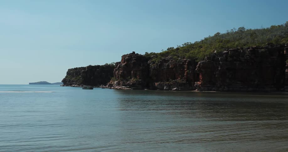 A large body of water near a forested rock hill