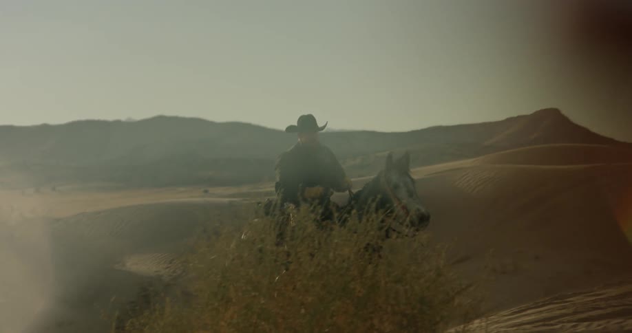 A man rides a horse up a sandy slope