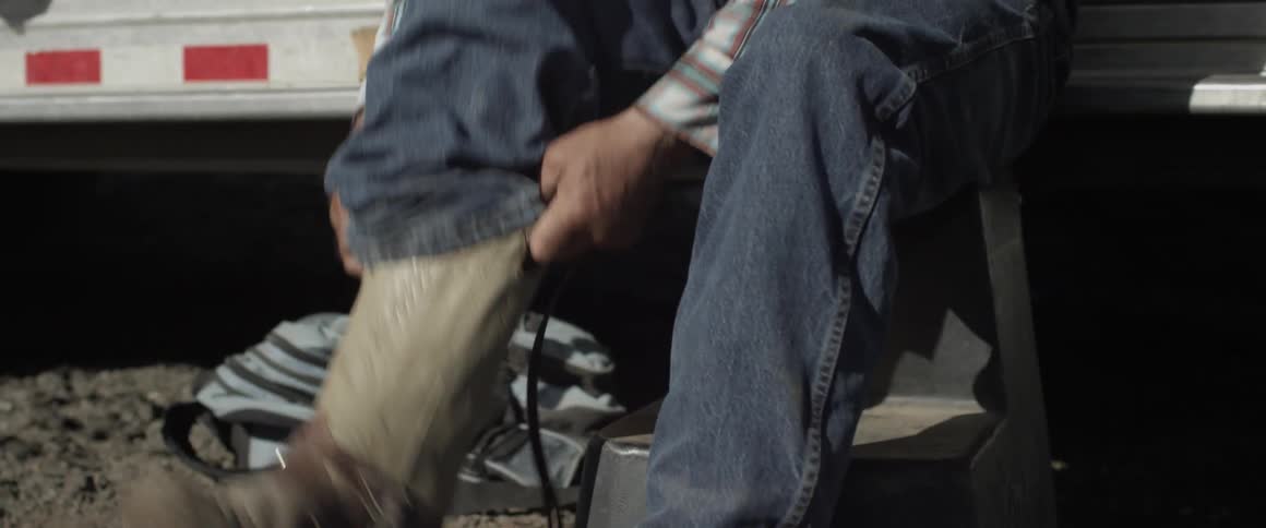 Man puts on cowboy boots outside