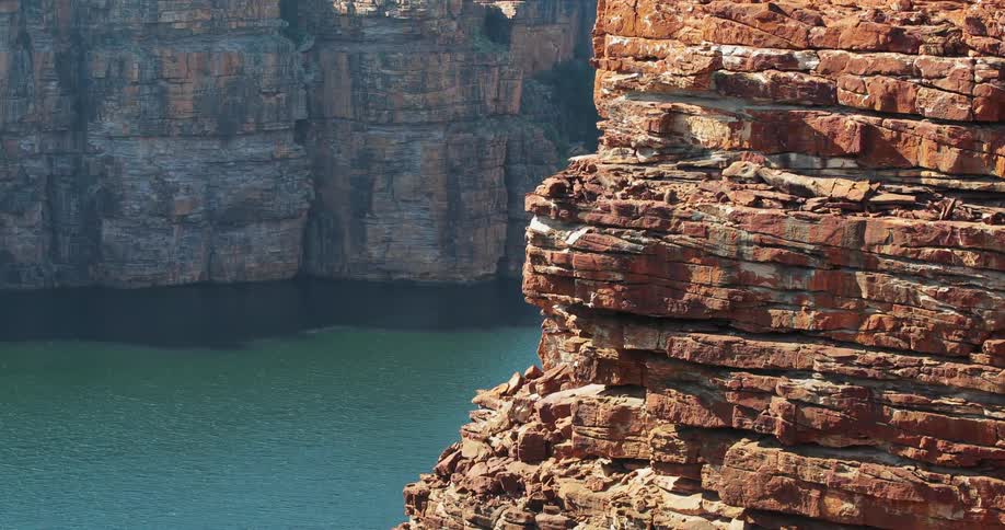 A red rocky mountain near a body of water