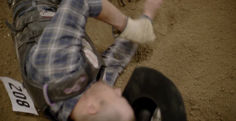 A cowboy is thrown to the ground at a rodeo
