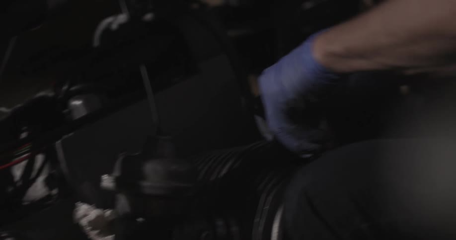 A person wearing plastic gloves works on a piece of equipment