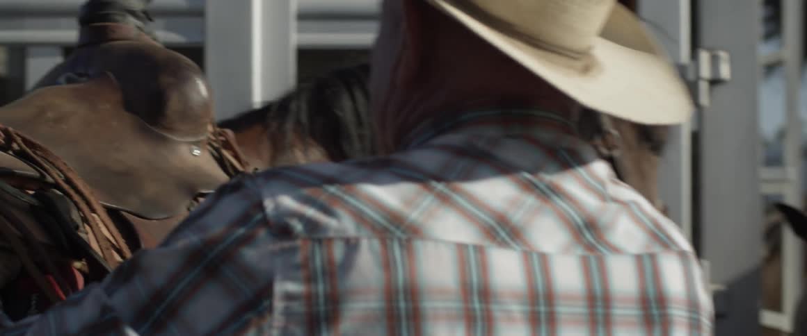 A man readying his horse and placing a saddle on it
