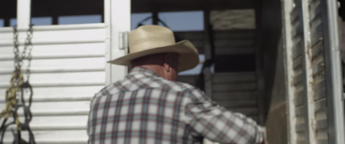 A man in a striped shirt climbs into a trailer