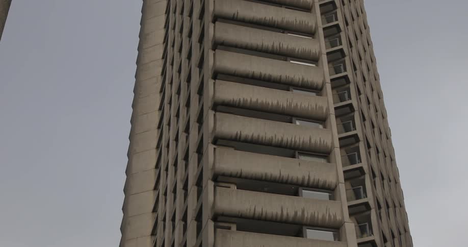 A skyscraper with rows of cement faced balconies against a gray sky